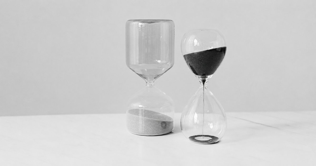 Two hourglasses on a table, one empty and one with sand still running
