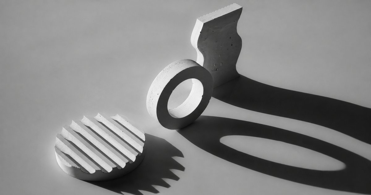 Concrete shapes casting long distorted shadows on a plain surface